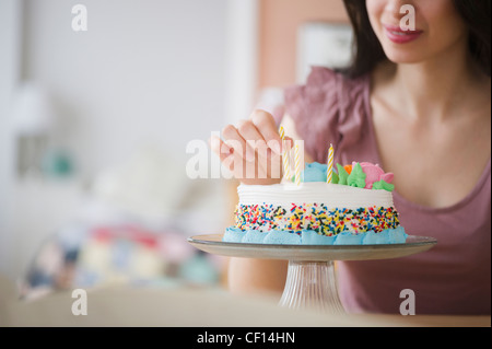 Gemischte Rassen Frau Vorbereitung Geburtstagstorte Stockfoto