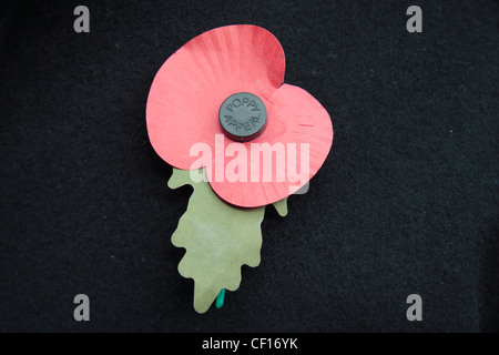 Eine englische künstliche Royal British Legion rote Mohn auf eine dunkle Jacke Hintergrund.  Dies zeigt das grüne Blatt nach oben. (06:00) Stockfoto