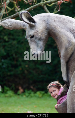 Junges Mädchen in der Tasche einer Modell-Statue eines Kängurus Stockfoto