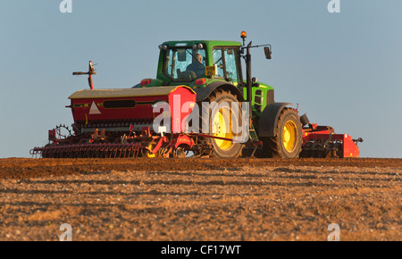 Ein Britischer Landwirt Einstellung eine Ernte mit einem landwirtschaftlichen Traktor und Drillmaschine Stockfoto