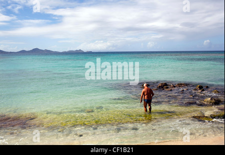 Ein Mann betritt das Wasser zu schwimmen an Campbell Bay auf Union Island, St. Vincent und die Grenadinen. Stockfoto