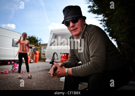 DALE FARM, BASILDON, ESSEX, UK, 15/09/2011.Dale Hof ansässige sitzt vor seinem Haus, während seine Enkelin im Hintergrund spielt. Stockfoto