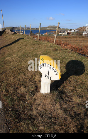 Alte Straße Marker aus 1897 zeigt die Entfernung zum Iona Fähre von Fionnphort, Isle of Mull mit Iona über das Meer gesehen Stockfoto