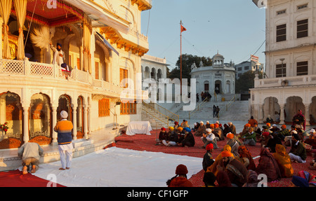 Sikhs beten vor einem Priester auf dem Gelände der goldenen Tempel in Amritsar, Punjab, Indien Stockfoto