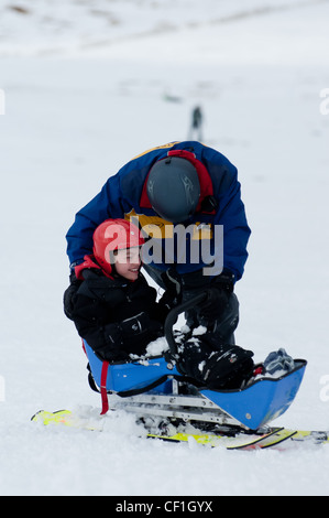 Behinderter junge in Schlitten lächelnd nach den Erfahrungen Stockfoto