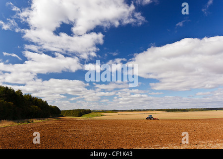 Traktor pflügen ein großes Feld auf dem Lande in der Nähe von Cirencester. Stockfoto