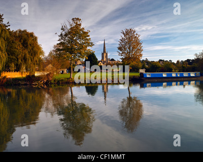 Eine schmale Boot vertäut an der Themse in Lechlade mit St. Lawrence Kirche im Hintergrund. Stockfoto