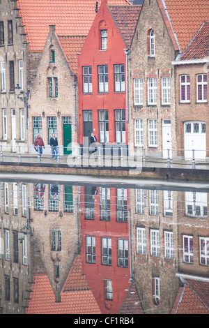 Ein Blick auf eine Terrasse von traditionellen Häusern spiegelt sich in den stillen Wassern eines Kanals in Brügge Stockfoto