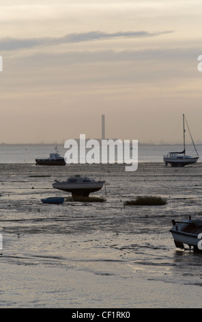 Kleine Boote vor Anker in der Mündung bei Leigh-on-Sea in Essex mit einer Fabrik in weiter Ferne. Stockfoto