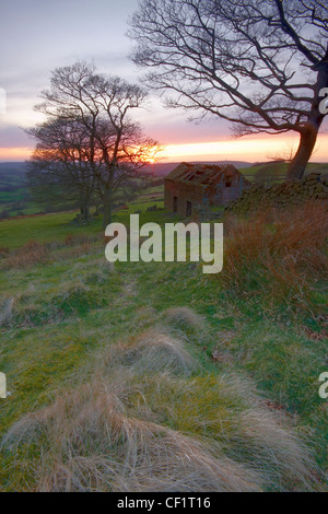 Sonnenuntergang über einem stillgelegten Bauernhof Gebäude am Roach End Farm im Peak District. Stockfoto