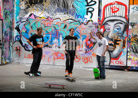 Skateboarder vor dem Hintergrund der Graffiti auf der South Bank in London. Stockfoto