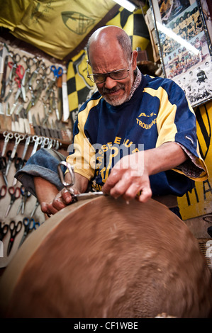 Lokale Mann Schärfen Scheren mit einem Schleifstein in seinem Geschäft, Fes, Marokko Stockfoto