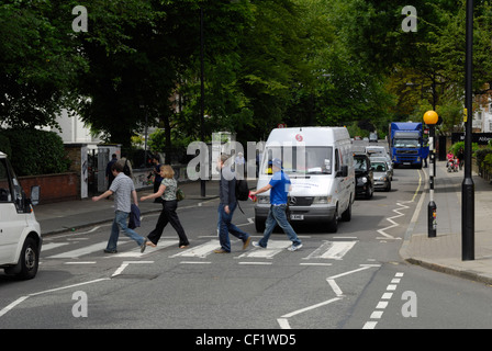 Touristen zu Fuß über den berühmten Abbey Road Fußgängerüberweg mit den Abbey Road Studios im Hintergrund. Viele berühmte Kunstwerke Stockfoto