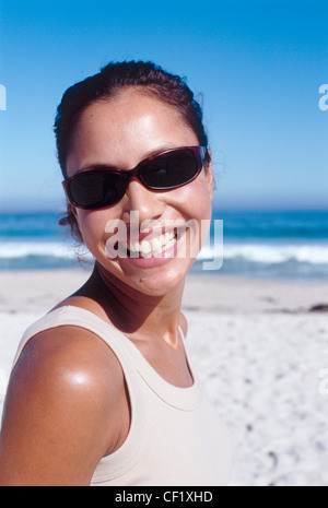 Semi-Profil des weiblichen wellige brünette Haare aus Gesicht trägt Schildpatt Sonnenbrillen und Beige Weste Top, Blick auf Kamera Stockfoto