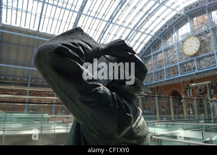 Eine Statue des Dichters John Betjeman von Martin Jennings in St. Pancras International Station, mit der berühmten Uhr im Hintergrund. Stockfoto