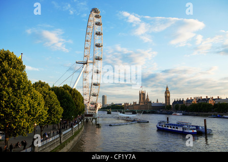 Ein Blick auf das London Eye von der Hungerford Bridge mit den Houses of Parliament in der Ferne Stockfoto