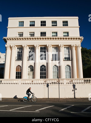 Ein Mann mit Radfahren stuckierter ein 'Boris Bike"vorbei an einem 19. Jahrhundert vom Architekten John Nash in Cumberland Terrasse. Stockfoto