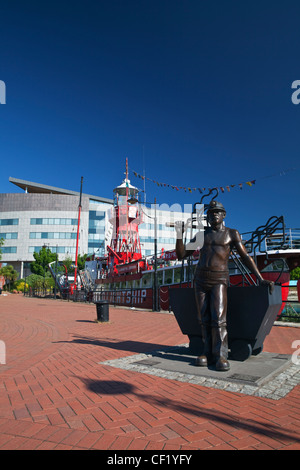 Bronzestatue eines Bergmanns durch das Feuerschiff Helwick LV14 in Cardiff Bay. Das Feuerschiff wurde 1993 restauriert und dient nun als ein Stockfoto