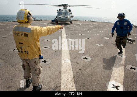 ARABIAN GULF (Feb 17, 2012) Seaman Cassandra Collier signalisiert Boatswains Mate Seaman Alonzo Bender, das Flugdeck zu verlassen, nachdem er einen MH-60S Sea Hawk Hubschrauber an das Deck des amphibischen Hafenlandungsschiffes USS Pearl Harbor (LSD 52) gekettiert und verketcht hat. Pearl Harbor und Einschiffung Marines der 11. Marine Expeditionary Unit (11. MEU) werden als Teil der Makin Island Amphibian Ready Group eingesetzt. Stockfoto