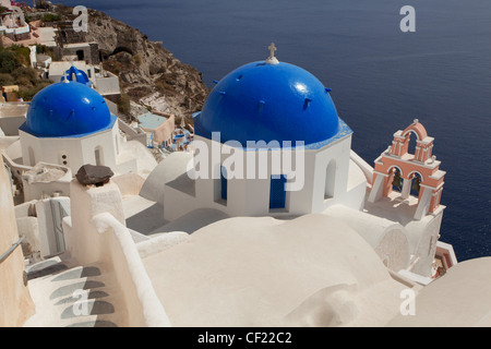 Ein Blick auf einige griechisch-orthodoxe Kirche Kuppeln thront auf einem Felsen über dem Meer und die Caldera von Santorin Stockfoto