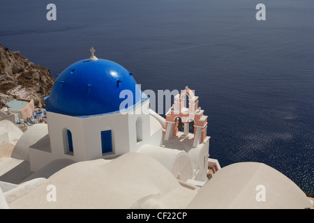 Ein Blick auf einige griechisch-orthodoxe Kirche Kuppeln thront auf einem Felsen über dem Meer und die Caldera von Santorin Stockfoto