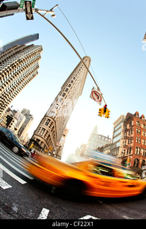 Der Flatiron-Keil geformte Gebäude in New York schießen in die Sonne lange Schatten Ampeln hellen Sonnentag beschäftigt Hauptverkehrszeit Stockfoto