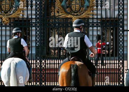 Polizisten und einer Königinnenwache diensthabenden außerhalb Buckingham Palace montiert. Stockfoto