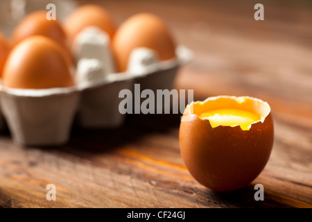 Eierschale mit Eigelb auf Holz eröffnet Stockfoto