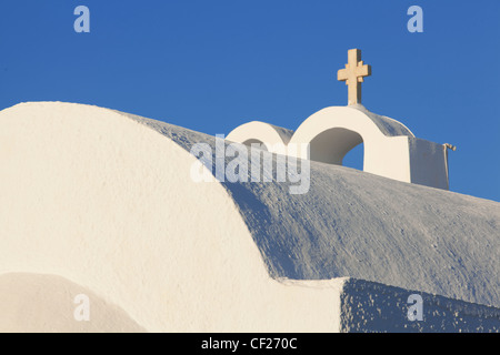 Ein Blick auf einen Glockenturm auf einer Kirche in Oia, umrahmt von einem tiefblauen Himmel Stockfoto