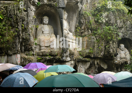 Kalkstein Buddha Skulpturen in feilai Feng im Regen mit Sonnenschirmen ling Yin Tempel Hangzhou China Stockfoto