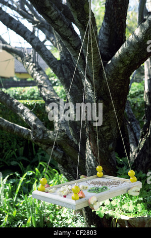 Offen ein Restaurant A Vogel Vogelhaus hängen an einer Schnur aus Holz, verziert mit Samen und verschiedene Arten von Obst Stockfoto