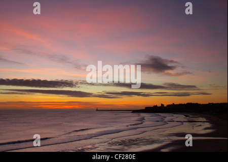 Sonnenaufgang mit Blick auf den Leuchtturm North Tyne Pier und Tynemouth Priory über Longsands. Stockfoto