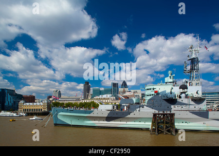 HMS Belfast, ursprünglich Royal Navy-Kreuzer, dauerhaft vor Anker in London auf der Themse mit City of London und Stockfoto