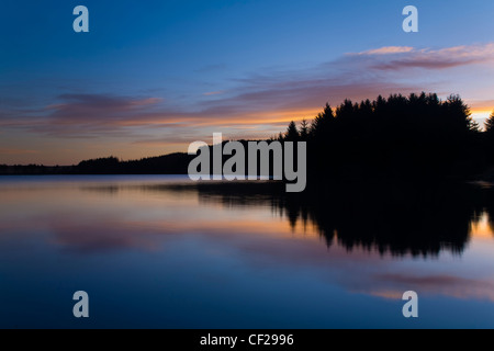 Sonnenaufgang wider in den ruhigen Wassern des Sees Alemoor, ein beliebter Ort für Sportfischerei in der Nähe der Stadt Hawick. Stockfoto