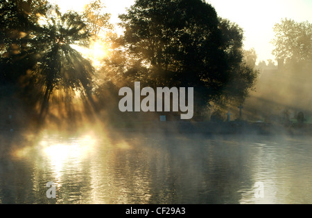 Sonnenstrahlen durch den Nebel am Bisham, mit Kirchhof im Hintergrund. Bisham ist Heimat einer der Nationalsportarten der Sport England Stockfoto