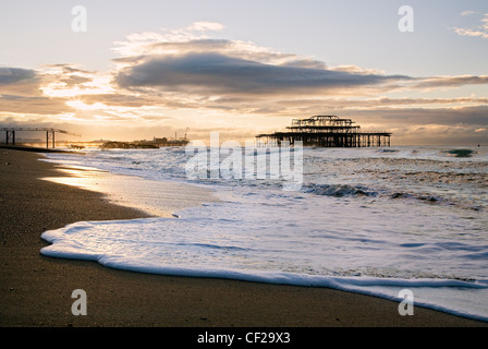 Eine Ansicht vom Strand in Richtung Sonnenaufgang über dem Brighton Pier. Stockfoto