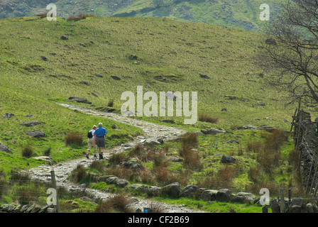 Ein älteres paar zu Fuß entlang einer felsigen Pfad im Lake District. Stockfoto