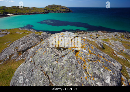 Das türkisfarbene Wasser des Achmelvich Bucht von den Flechten bedeckt Felsen an der Nordwestküste Schottlands. Stockfoto