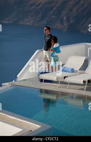 Ein paar Blick auf die Caldera von Santorin aus ihrem Hotel-Schwimmbad mit Dorf Oia in der Ferne Stockfoto