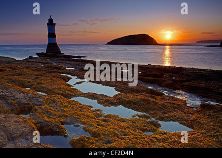 Penmon Leuchtturm, auch bekannt als Menai Leuchtturm am Nordeingang, die Menaistraße gegenüber Puffin Insel bei Sonnenaufgang. Stockfoto