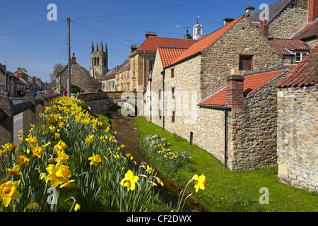 Rathaus, All Saints Church Tower und Steinbrücke über Stream ausgekleidet mit Narzissen in das Dorf Helmsley am Rande des N Stockfoto