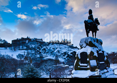 Denkmal für die Royal Scots Greys am Princes Street Gardens, mit Blick auf Edinburgh Castle unter einer Schneedecke. Stockfoto