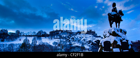 Denkmal für die Royal Scots Greys am Princes Street Gardens, mit Blick auf Edinburgh Castle unter einer Schneedecke. Stockfoto