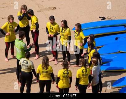 Junge Menschen erhalten Anweisungen an eine Surfschule am Strand in Newquay. Stockfoto