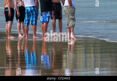 Eine Gruppe von männlichen Urlauber stehen auf dem Vorland der Strand bei Ebbe. Stockfoto