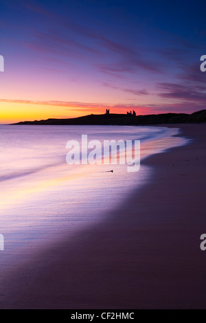 Eine bunte Anzeige von vor Sonnenaufgang Farben Popularitätswert auf dem nassen Sand Embleton Bay, überragt von den dramatischen Ruinen von Dunstan Stockfoto