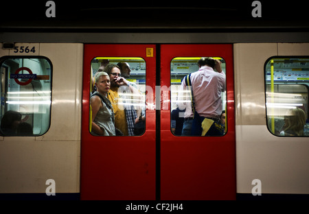 Pendler stehen an Bord ein Londoner U-Bahn u-Bahn Zug. Stockfoto