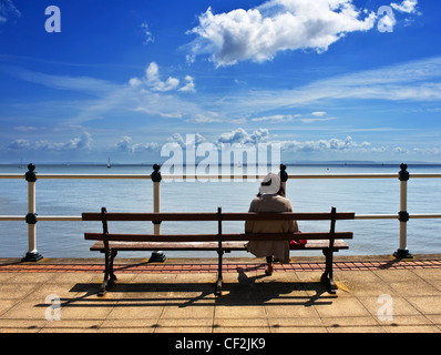 Eine Frau sitzt auf einer Bank, Blick auf das Meer auf Penarth Esplanade. Stockfoto