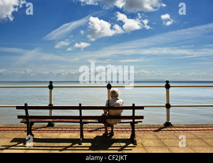 Eine ältere Frau sitzen auf einer Bank, Blick auf das Meer auf Penarth Esplanade. Stockfoto