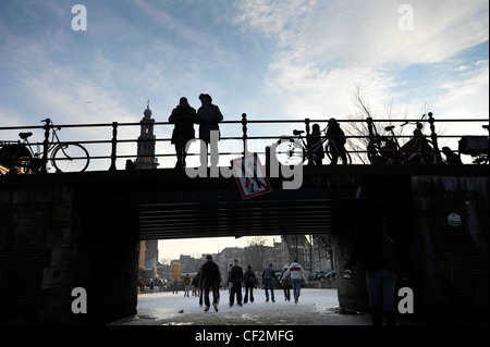 Die Menschen gehen auf zugefrorenen Kanälen im Zentrum von Amsterdam, Niederlande. Stockfoto